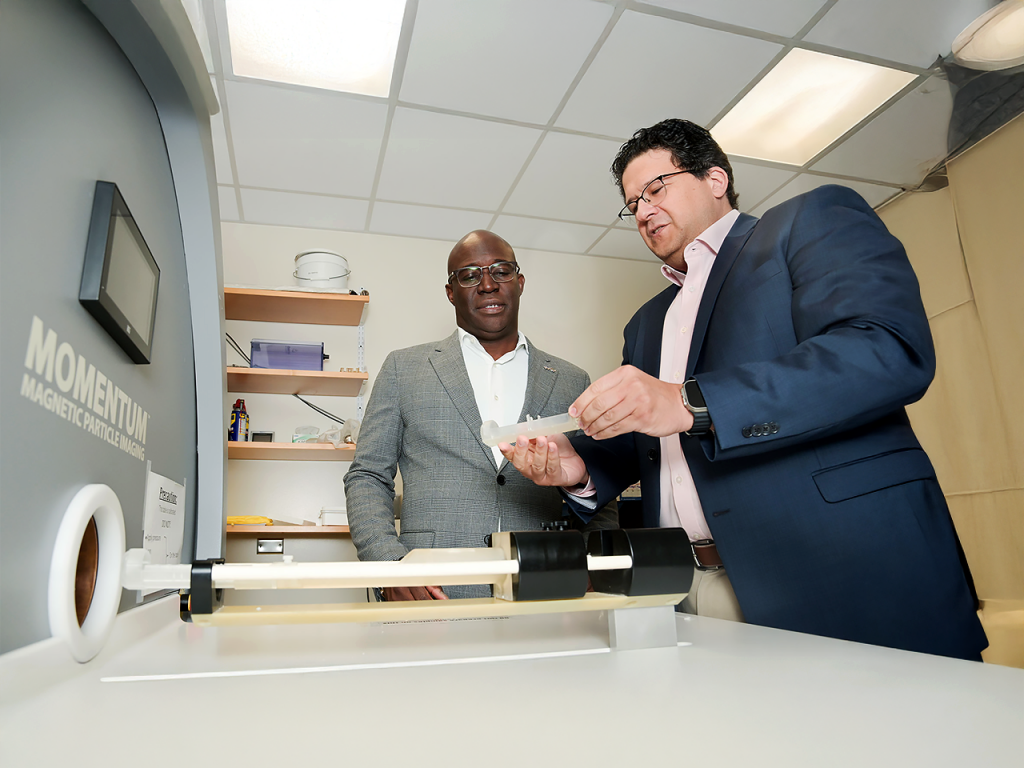 Duane Mitchell, M.D., Ph.D., left, and Carlos Rinaldi-Ramos, Ph.D., by UF's magnetic particle imaging scanner.